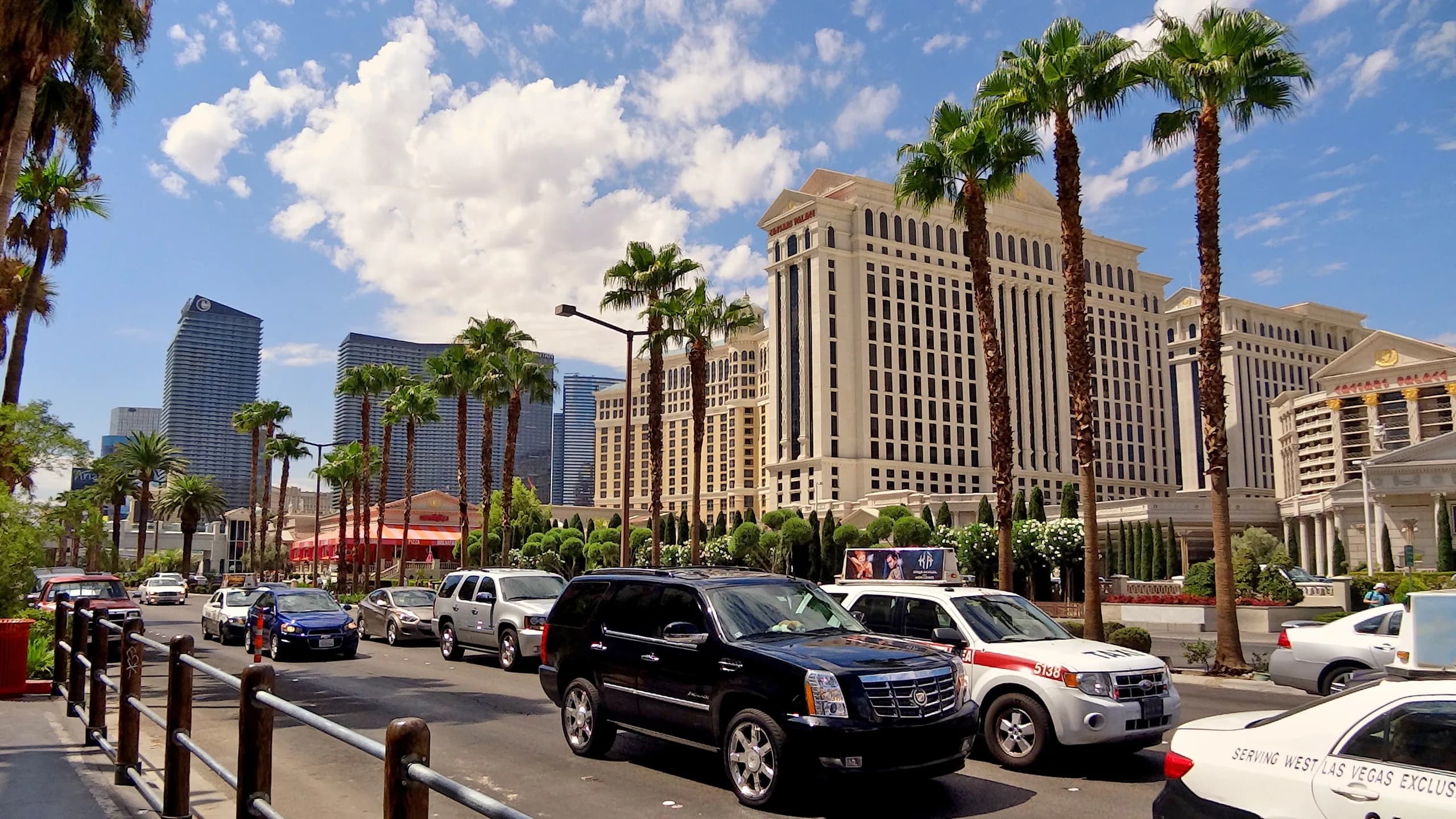 Der Las Vegas Strip bei Tag mit Palmen und dem Caesars Palace, davor Autos und Taxis auf der Straße